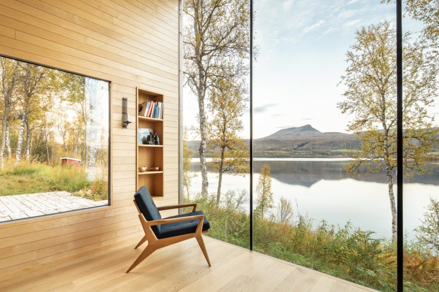 The reading nook inside a cabin, with large windows facing out towards the water.