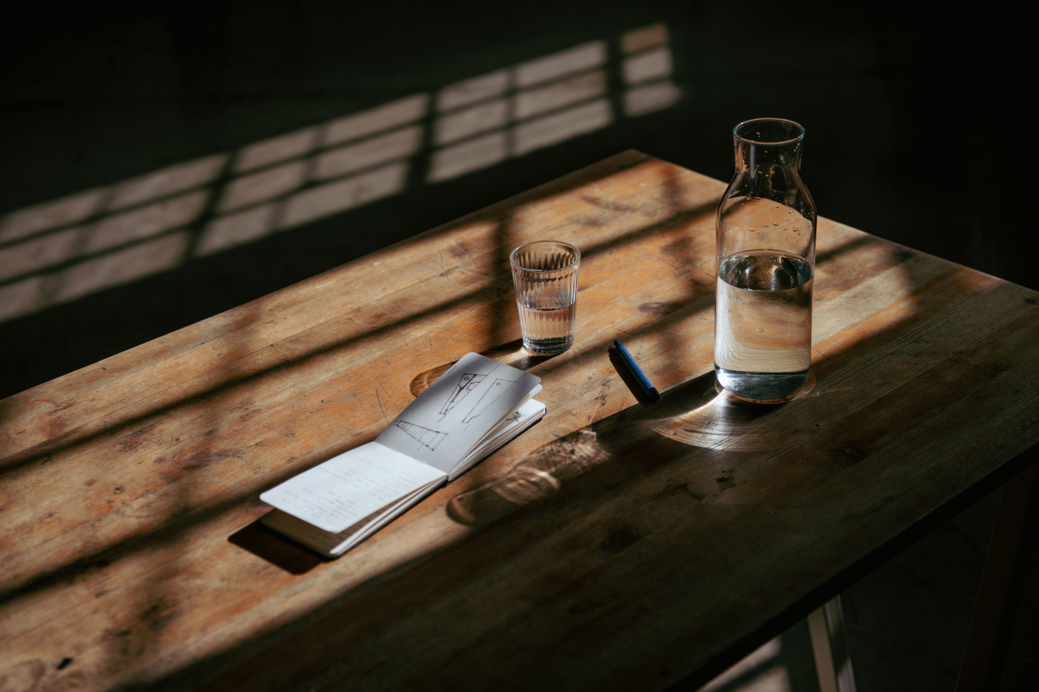 A notepad, water pitcher, and a water glass on a table.