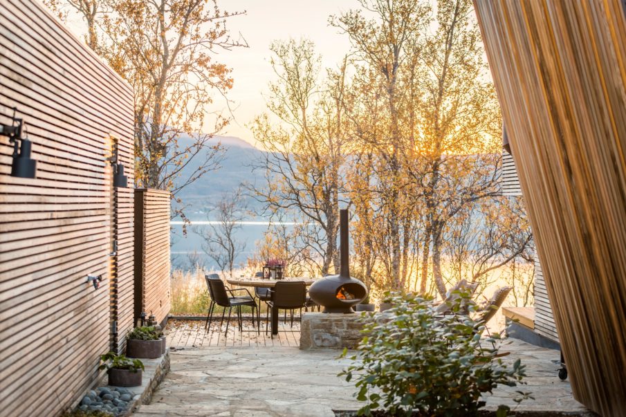 A cozy terrace with an outdoor fireplace and a view of the fjord.