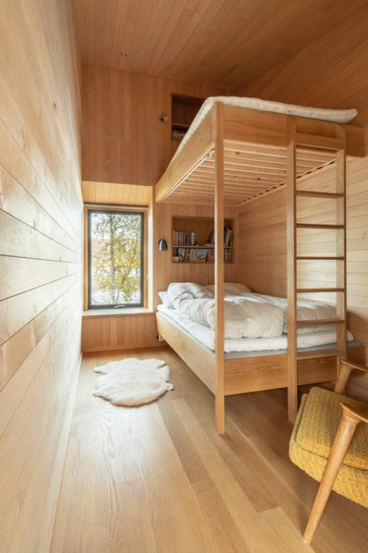 Bedroom with a wooden bunk bed, featuring a yellow armchair in the corner.