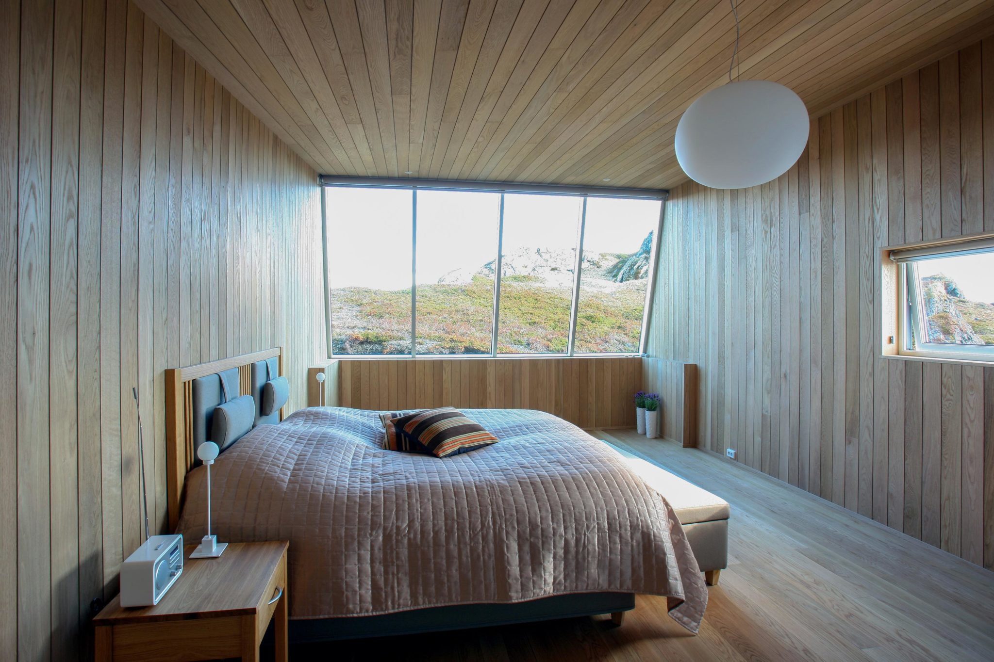 Bedroom with a kingsize bed and large windows on the left, leading you directly into nature.