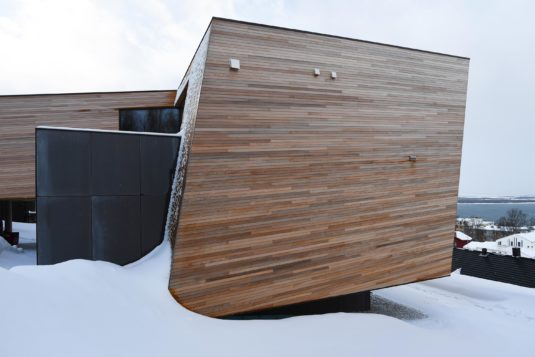 A modern cabin hovering above the snow-covered ground.